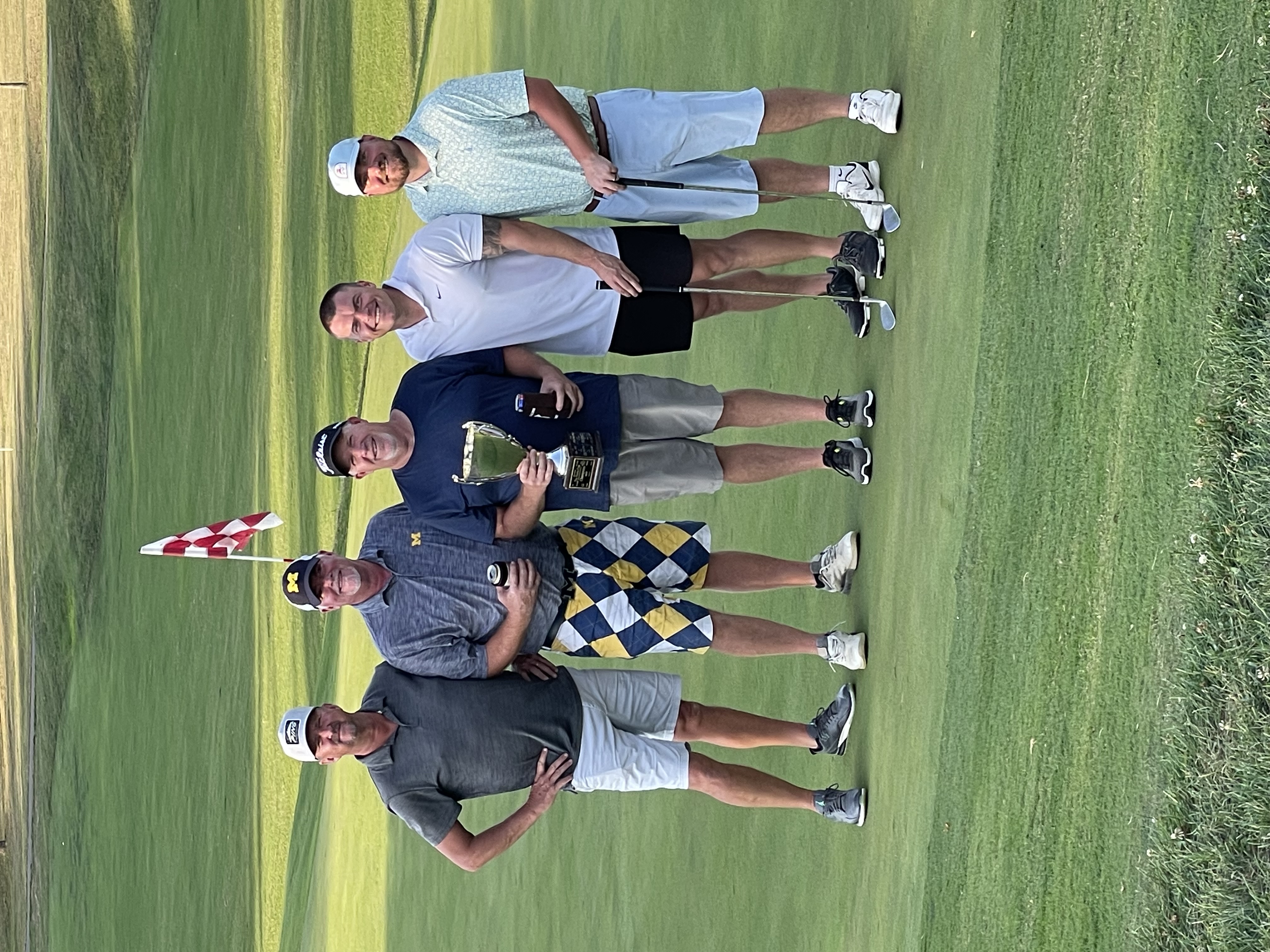Five players on the green at golden hour holding the Rosewood Cup